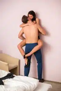 couple trying to have sex against a wall like in a movie